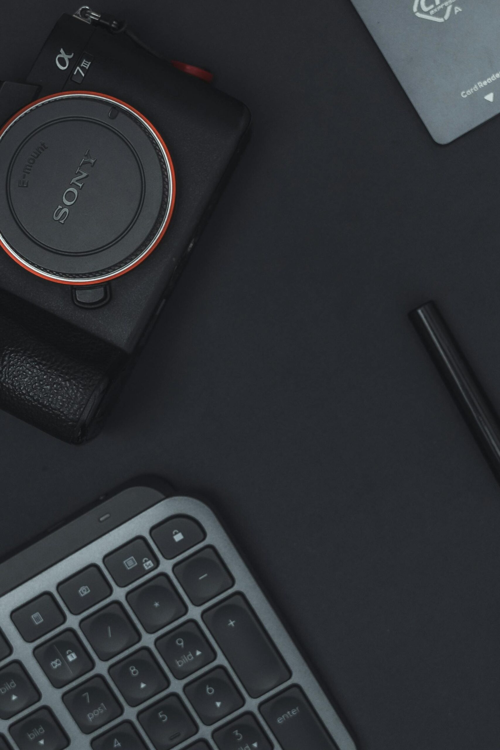 Minimalist flat lay showing a camera and keyboard on a dark surface, emphasizing technology and design.